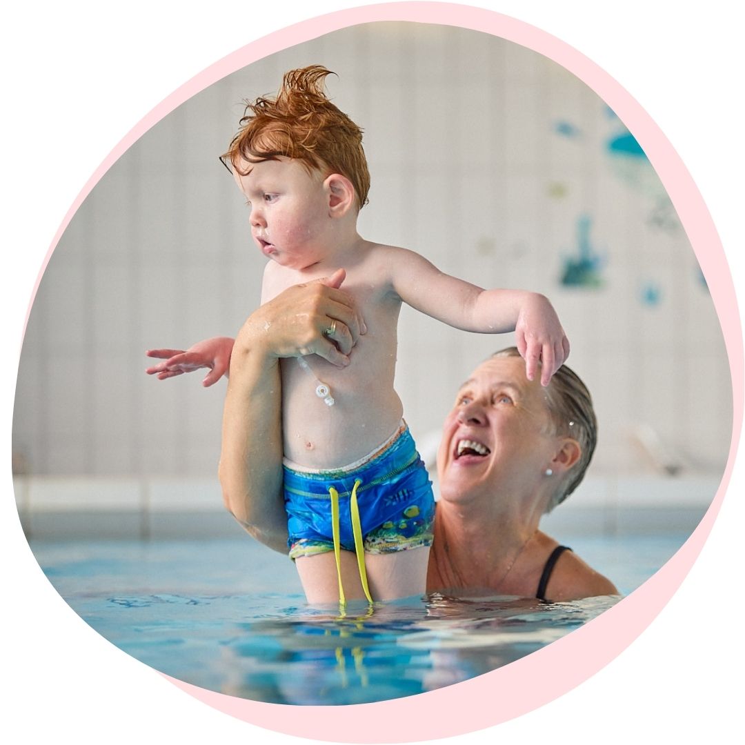 woman holding boy up in swimming pool
