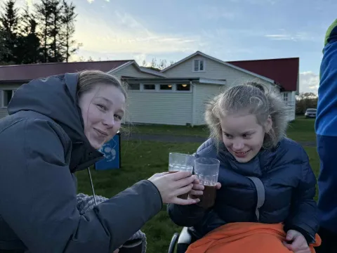 Tvær undir teppi að skála í heitu kakói við brennu