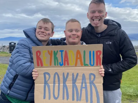 Þrír strákar að halda á Reykjadalur rokkar skilti að hvetja maraþonhlaupara