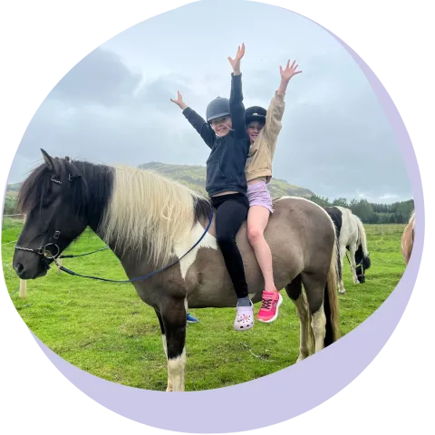 two kids on a horse with hands up in the air