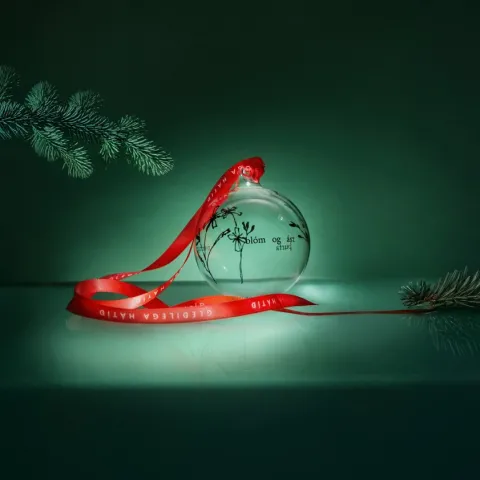 Kúlujólatré með rauðu borði á grænum bakgrunni.