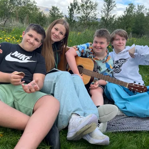 Kids sitting in grass with guitar