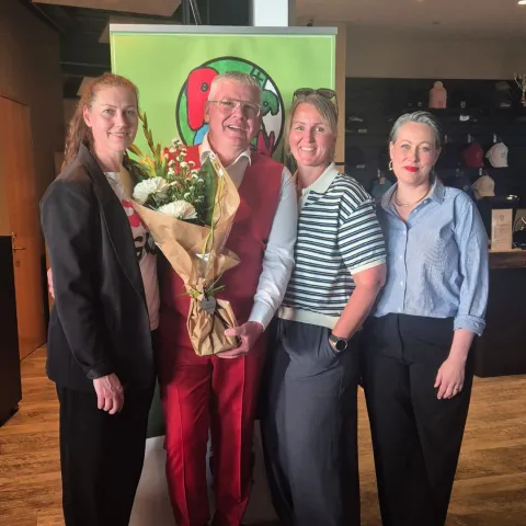 Four people posing with flowers
