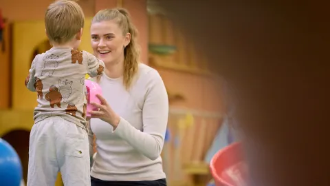 Kona brosir í átt að barni sem snýr baki