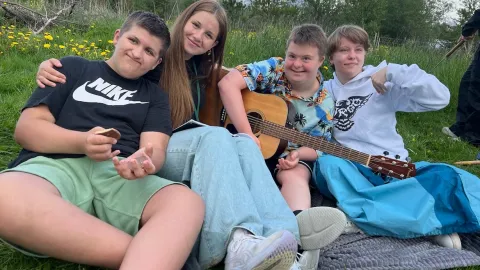 Kids sitting in grass with guitar