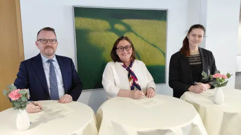 Three people signing documents