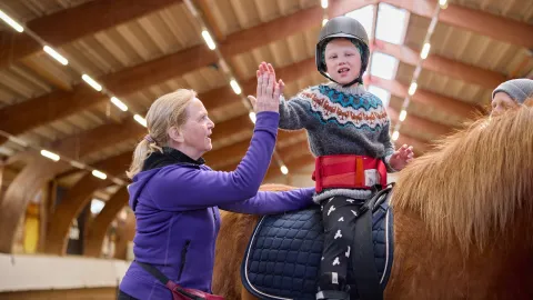 Boy giving high five on horse back