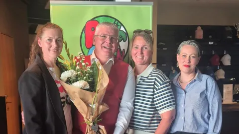 Four people posing with flowers